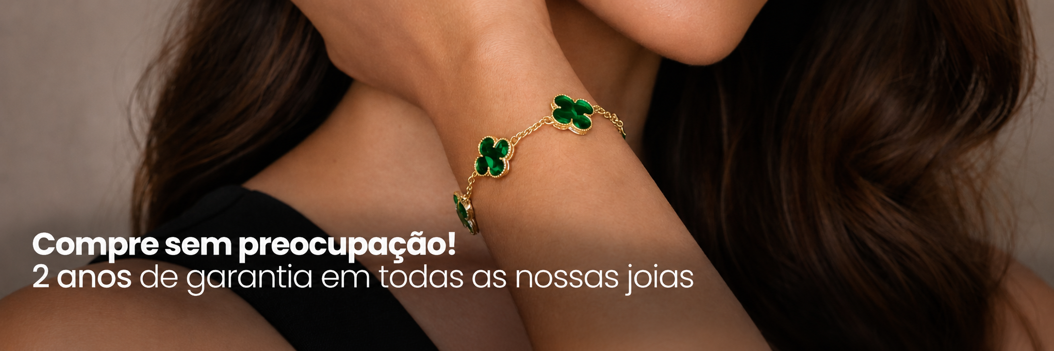 Modelo usando pulseira dourada com pingentes verdes da Helennea Semijoias. Texto: Compre sem preocupação, 2 anos de garantia em todas as nossas joias